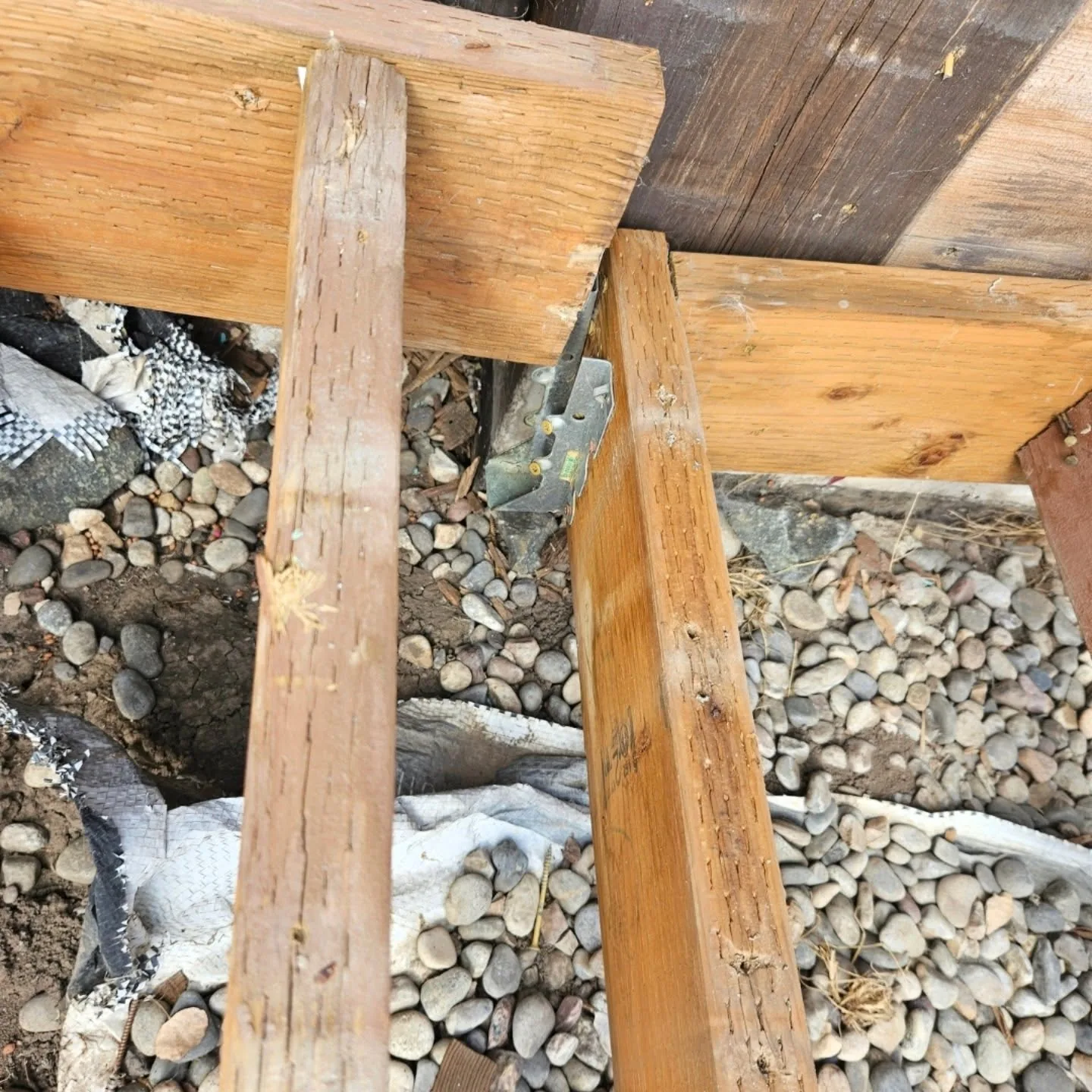 Close up metal joist hanger deck frame river rock