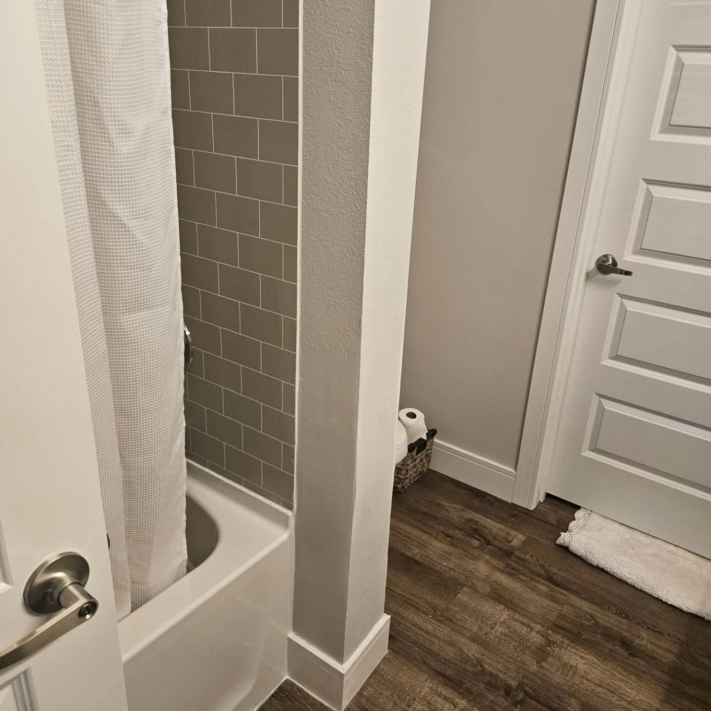 Gray subway tile tub surround dark vinyl floor