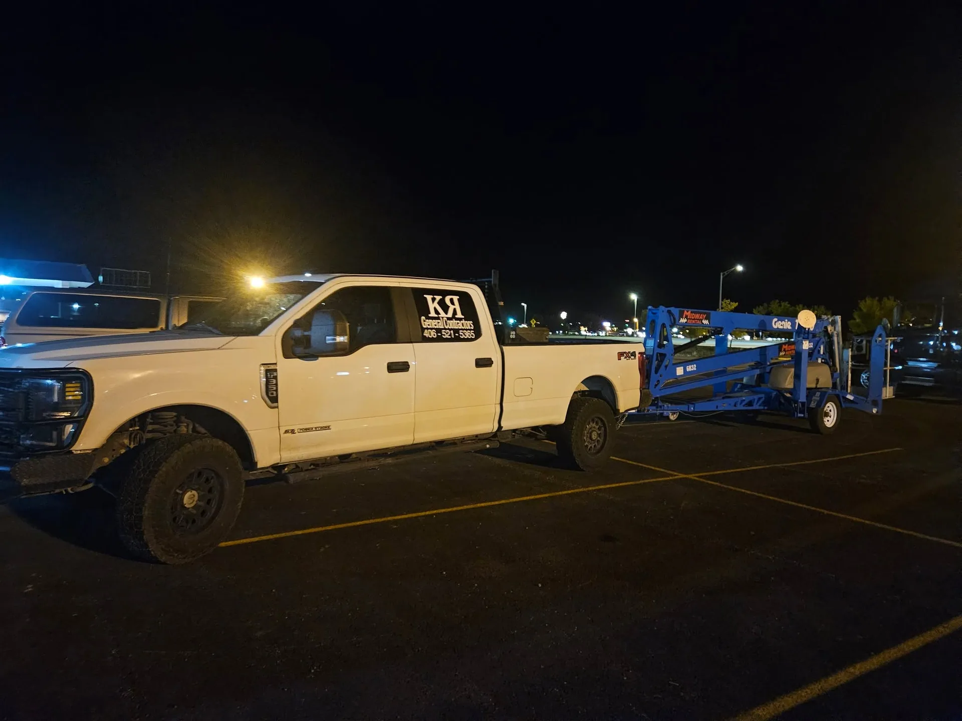 Kr contractors truck towing genie boom lift night