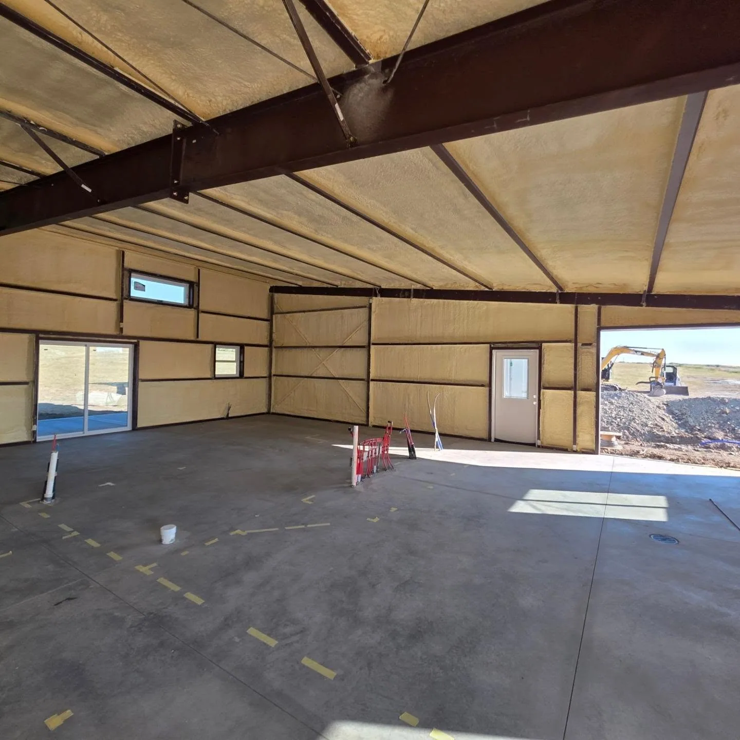 Open bay door excavator view spray foamed steel shop