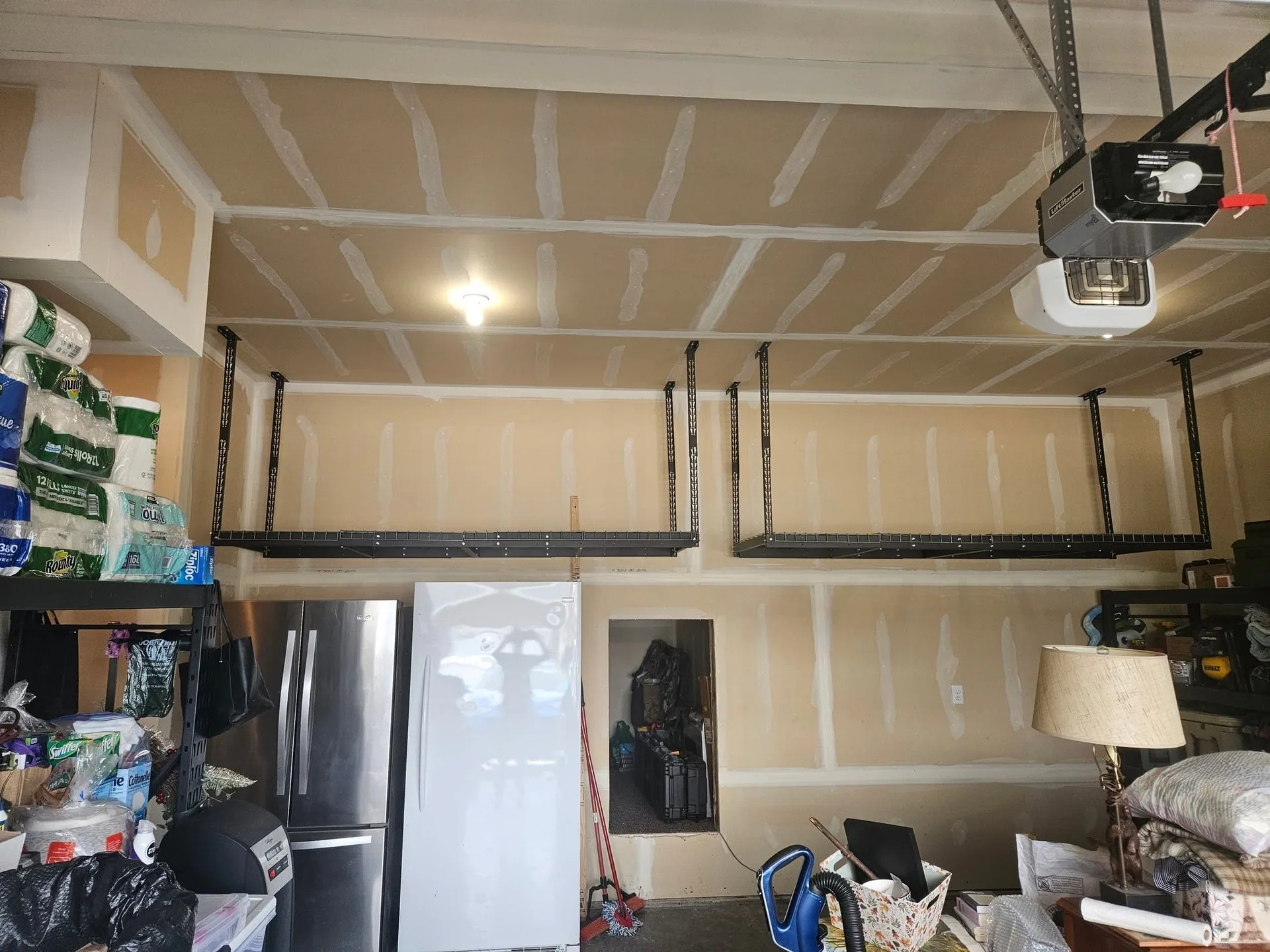 Overhead garage ceiling storage racks taped drywall