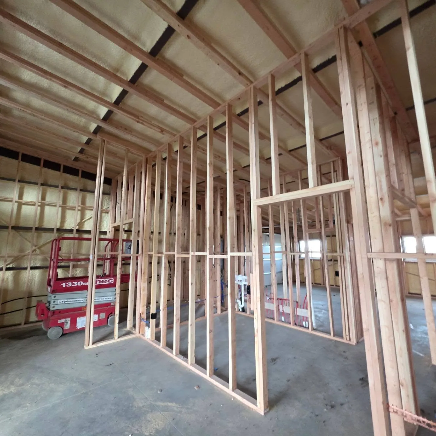 Red scissor lift wood stud framing spray foam shop