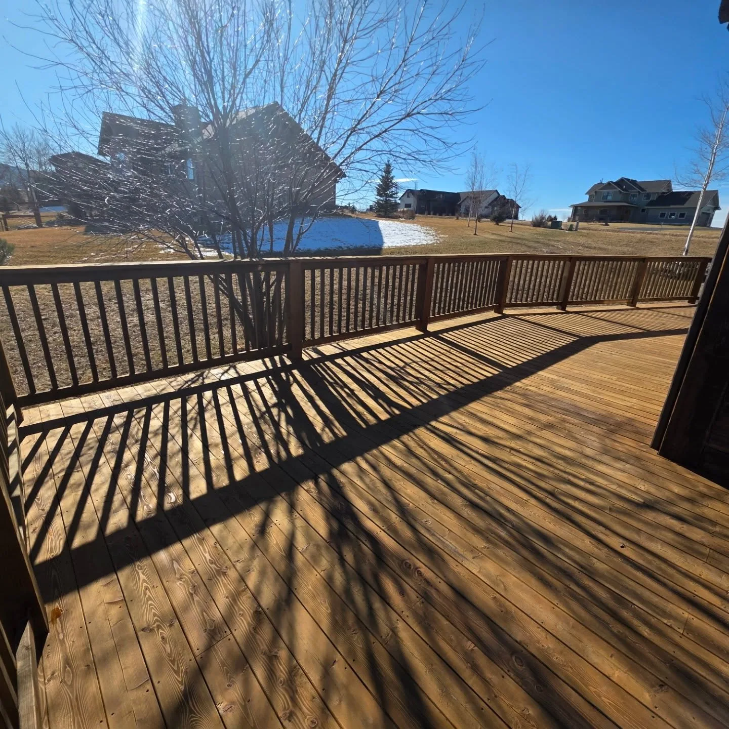 Wide angle stained deck bare tree shadow rural homes